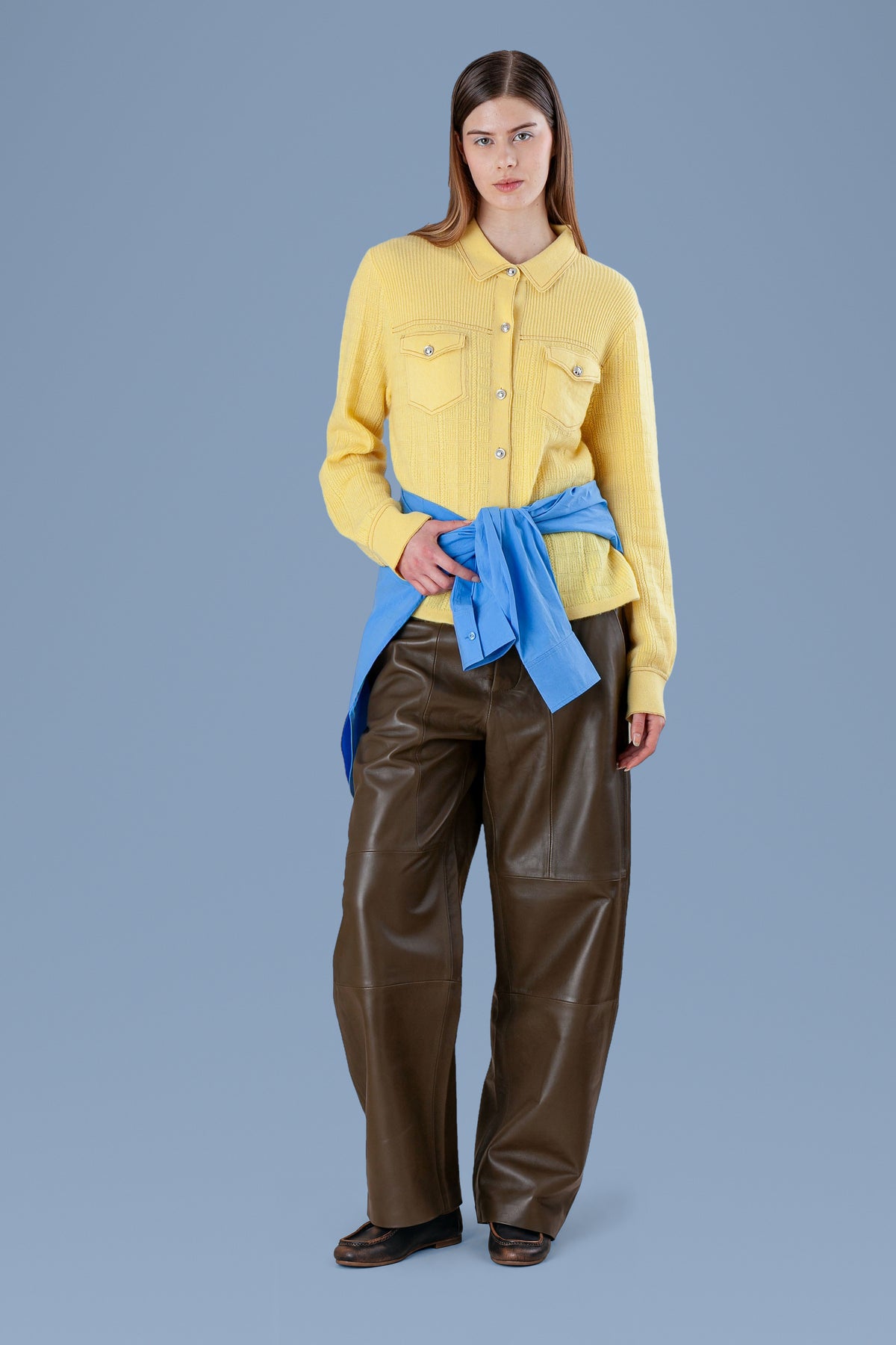 Yellow cashmere shirt worn with a blue sweater tied at the waist