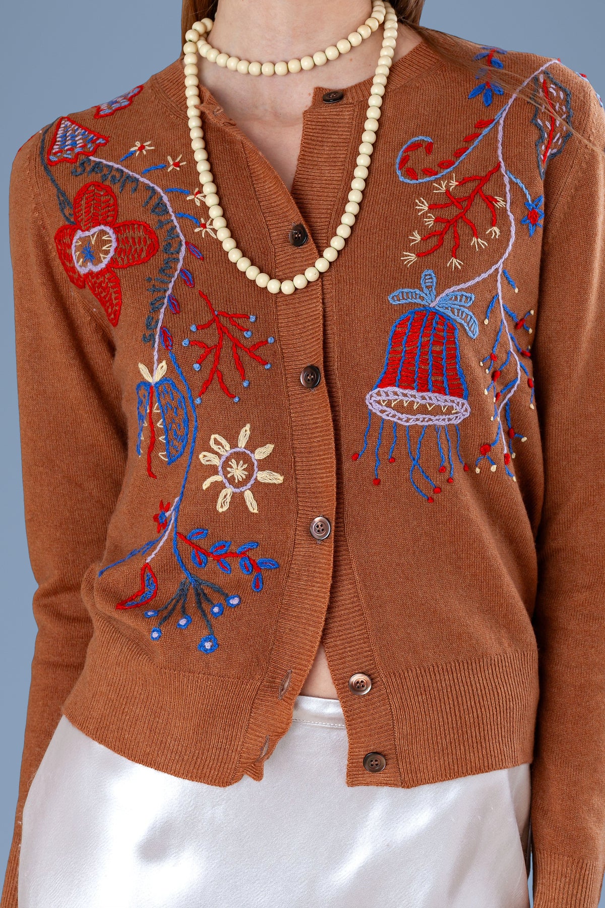 Close-up of hand embroidery and buttons on cuoio cardigan