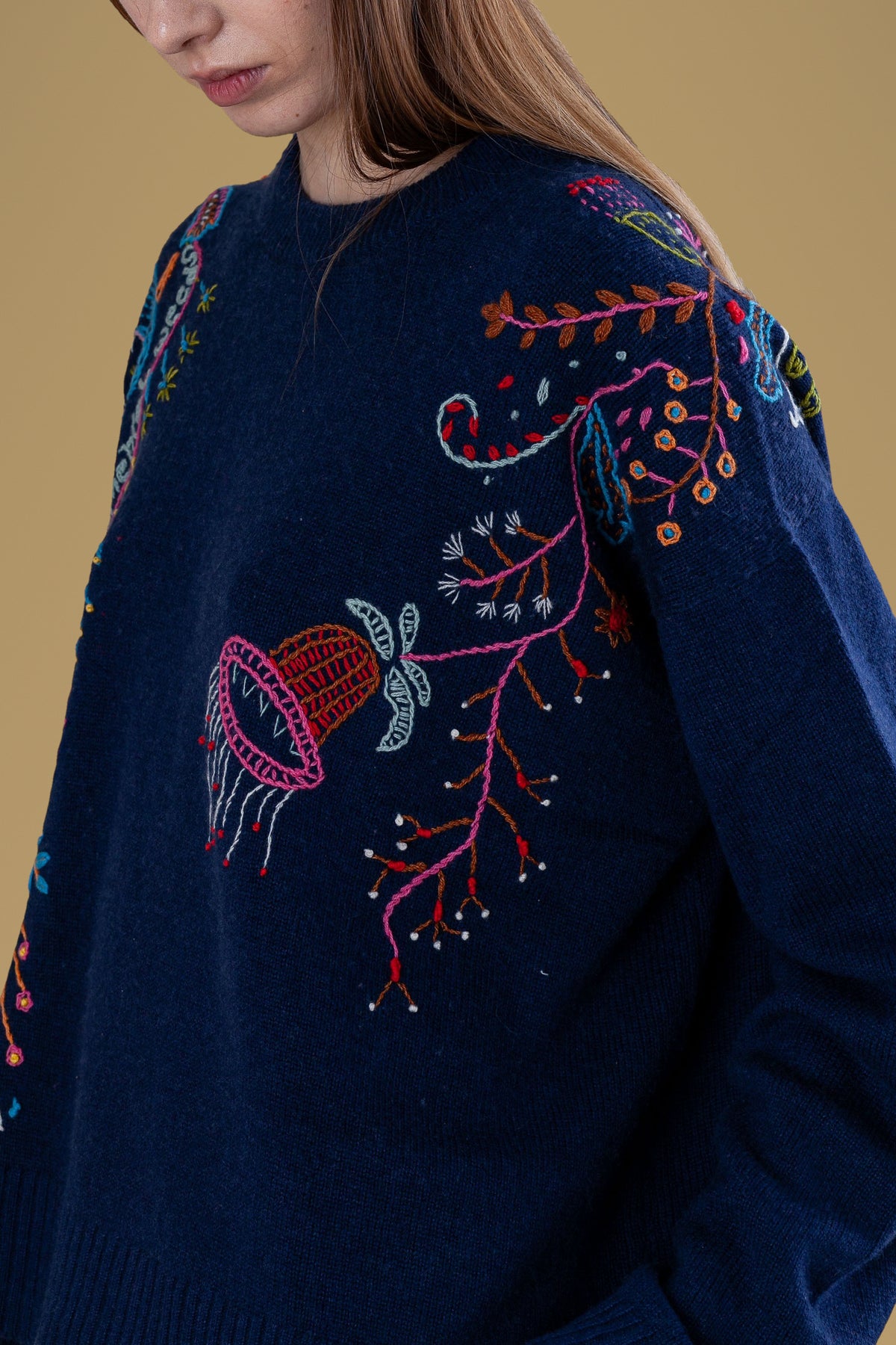 Close-up of hand embroidery: flowers and bell on navy knit