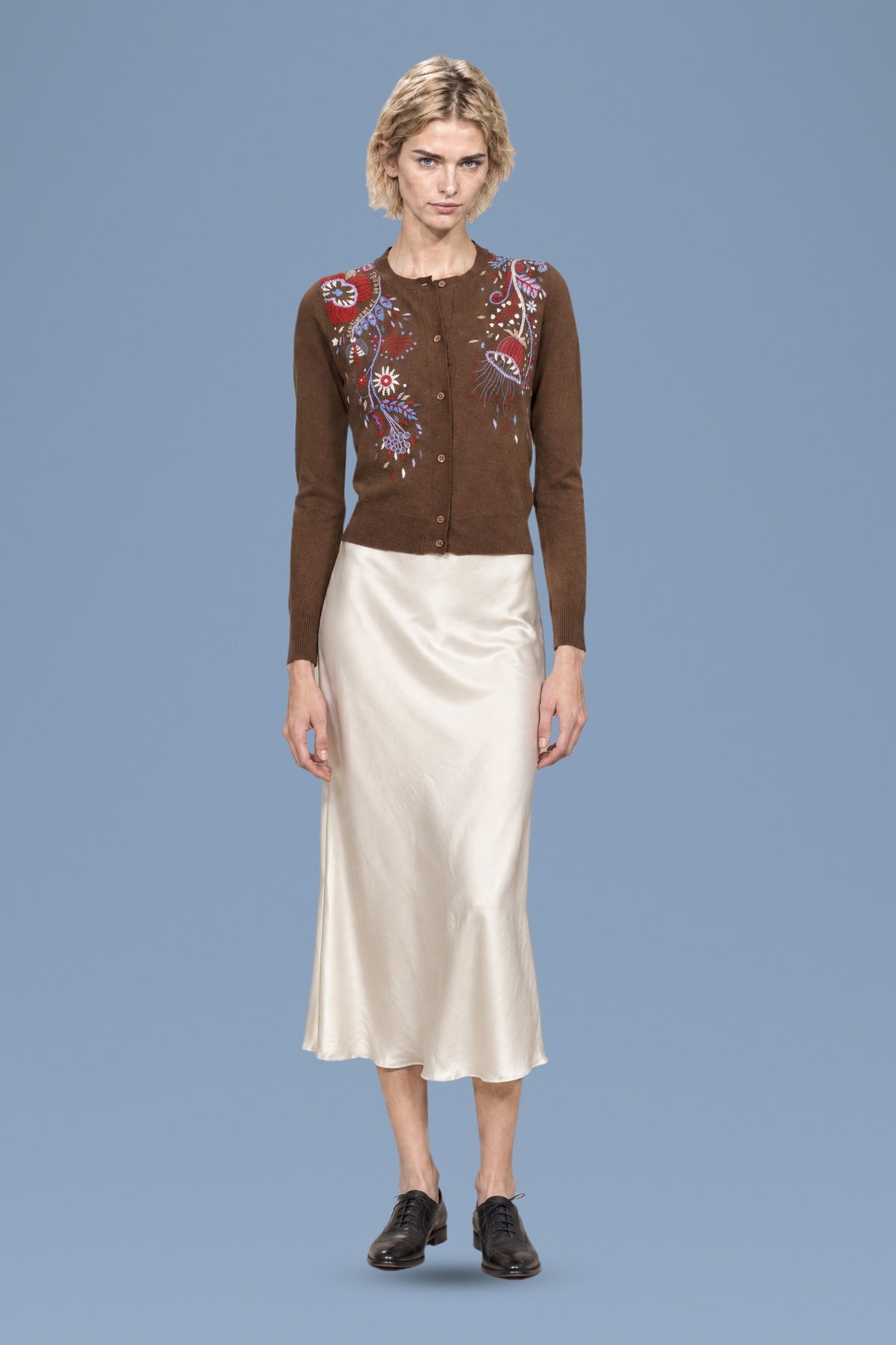 Brown hand-embroidered Rebecchina cardigan, front view, worn with an ivory satin skirt