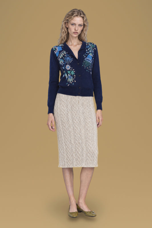 Navy hand-embroidered Rebecchina cardigan, front view, worn with a cream cable-knit skirt