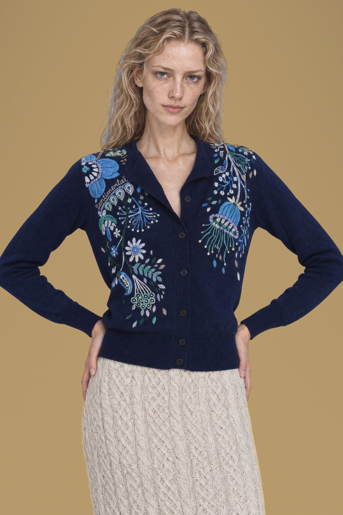 Navy Rebecchina cardigan, hands on hips, hand embroidery on both front panels