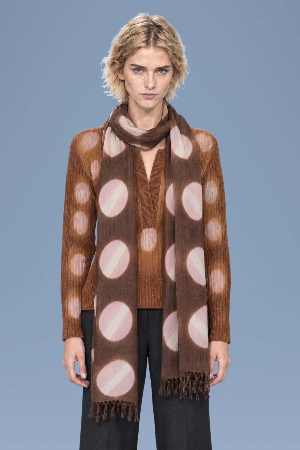 Brown tie-dye circles cashmere scarf worn long over a brown Henley sweater