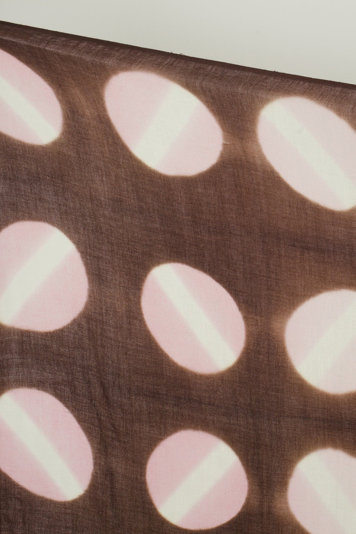 Close-up of the hand tie-dyed pink circles on the brown cashmere scarf