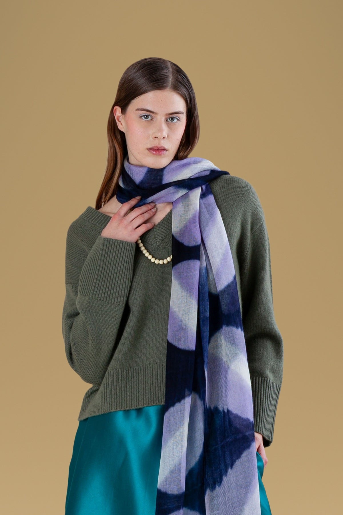 Navy tie-dye circles cashmere scarf worn over a green sweater